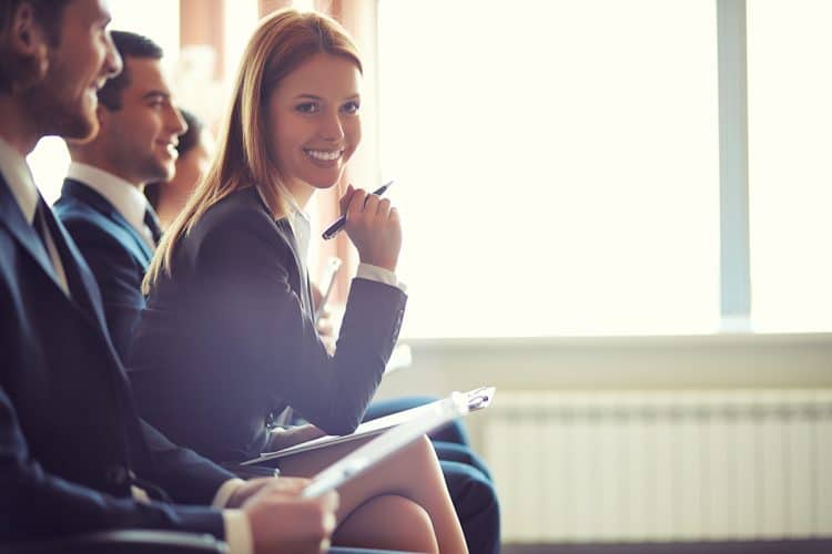 Row of business people sitting at seminar, focus on attentive young female